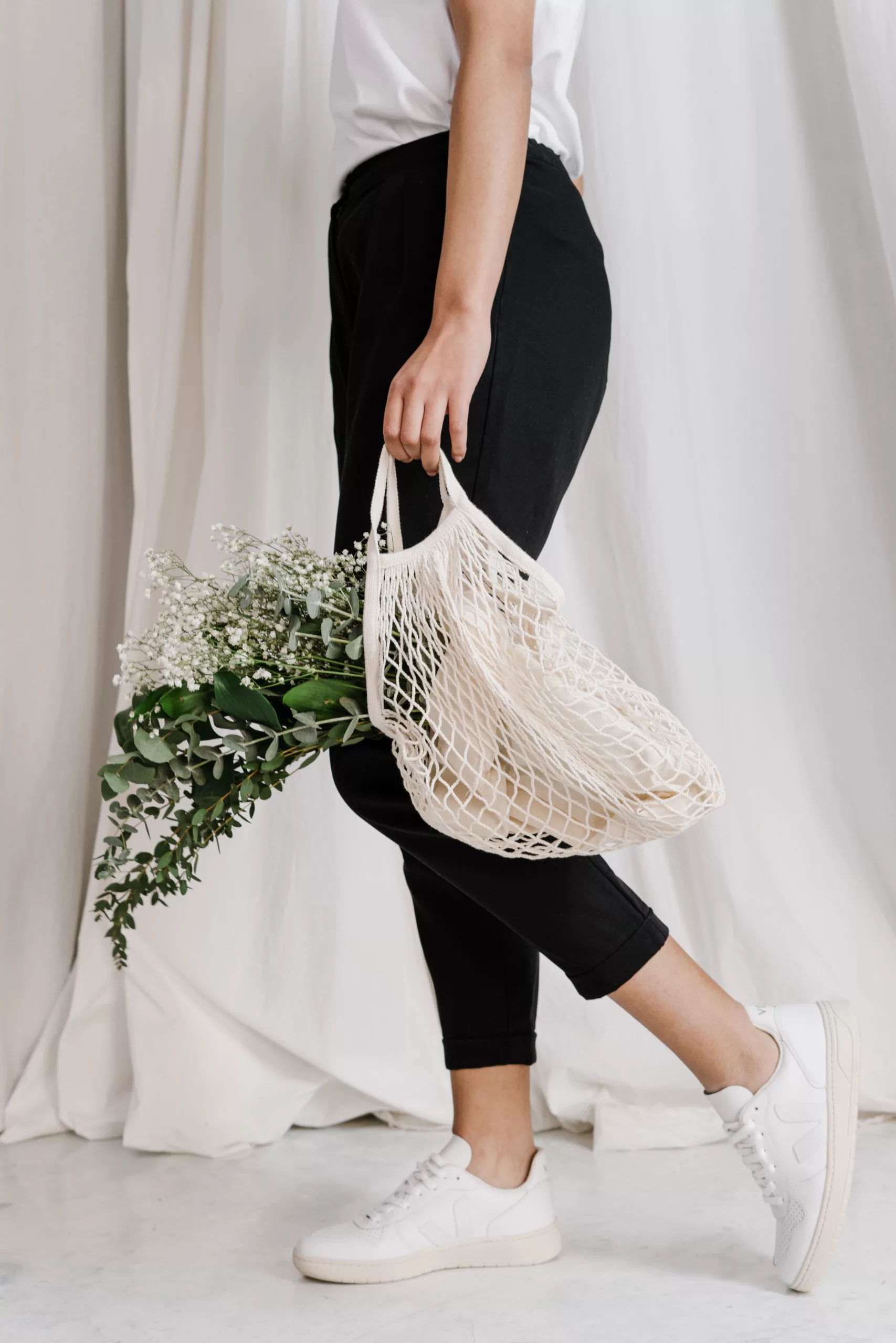 une personne revient de courses avec un totebag rempli de plantes