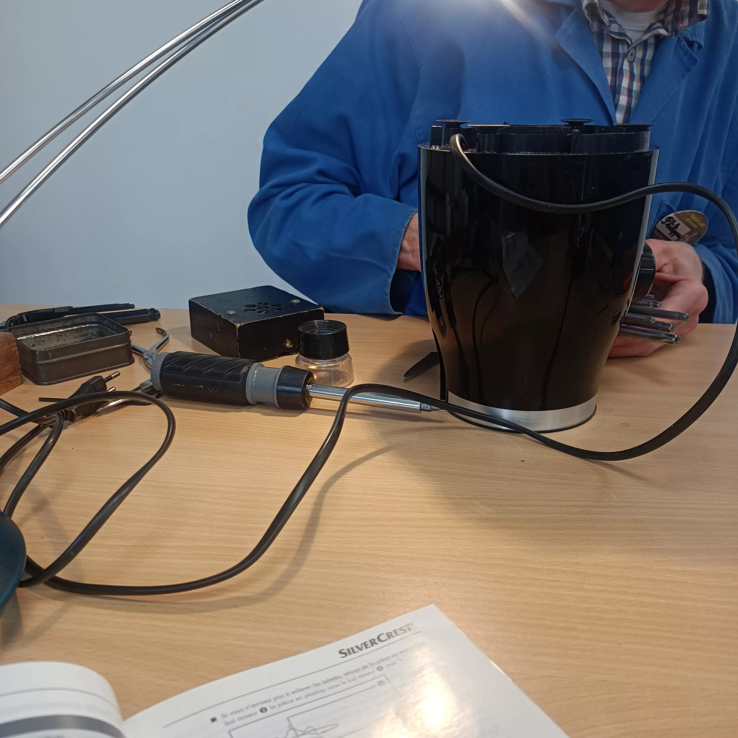 Un monsieur est en train de réparer un blender dans un repair café