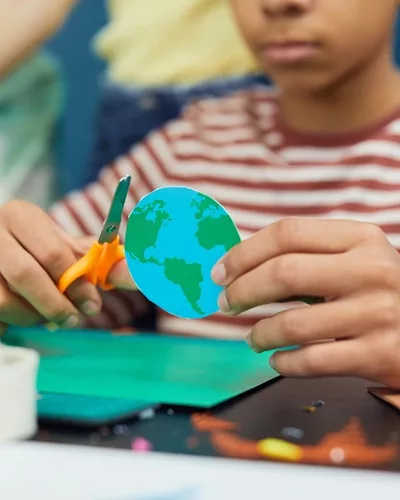 Enfant qui découpe une Terre en carton.