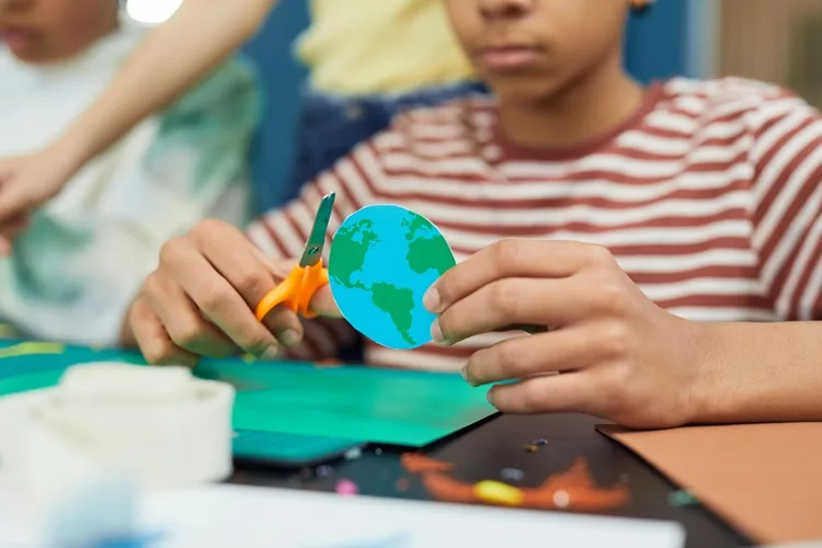 Enfant qui découpe une Terre en carton.