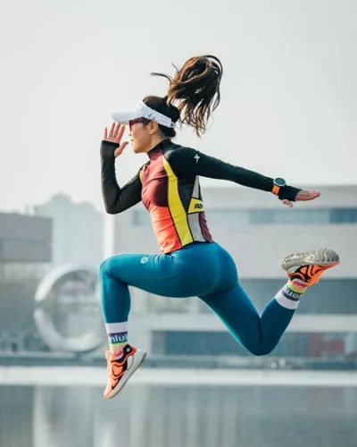Une sportive court et saute, habillée en tenue de sport.