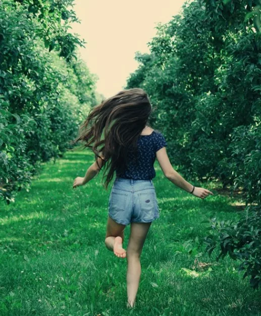 Une fille court dans l'herbe, les pieds nus.